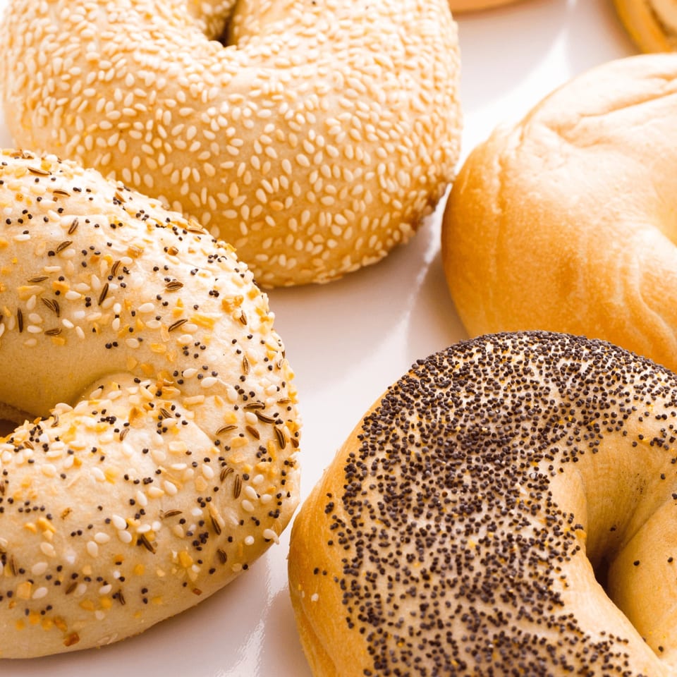 Assortment of Sarah's Bagel Cafe bagels, including sesame, everything, plain, and poppy seed varieties.